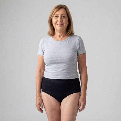 Woman wearing high-waisted black absorbent underwear for female incontinence, a washable and discreet solution for light to moderate bladder leaks, made from comfortable bamboo fiber with odor control for all-day freshness.